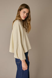 Maglione over a cappa panna, linea essenziale e silhouette versatile